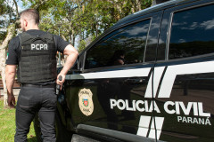 Policial civil ao lado de viatura