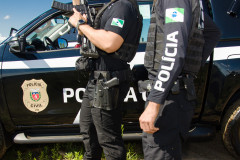 Dois policiais civis ao lado de viatura