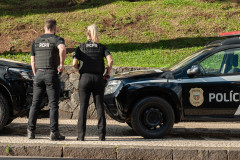 Dois policiais civis ao lado de viatura