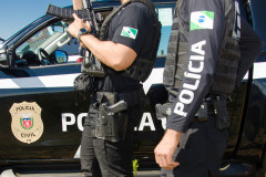 Dois policiais civis ao lado de viatura