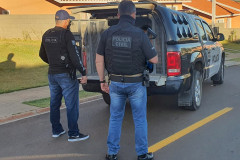 Dois policiais civis ao lado de viatura