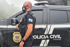 Policial civil ao lado de viatura