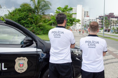 Dois policiais ao lado de viatura no litoral