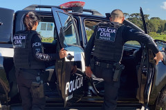 Dois policiais civis entrando em viatura