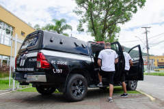 Dois policiais civis entrando em viatura em frente à delegacia