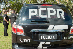 Dois policiais civis ao lado de viatura