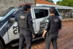 Dois policiais civis ao lado de viatura