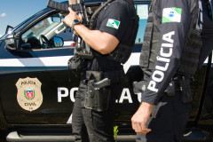 Dois policiais ao lado de viatura