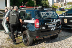 Dois policiais civis entrando em viatura