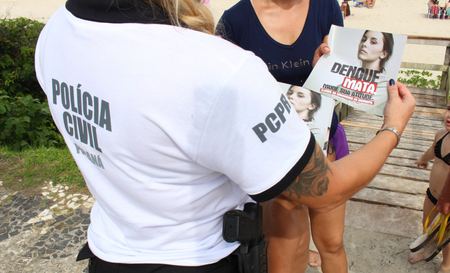 Policial civil entregando panfleto da campanha contra a dengue para veranista