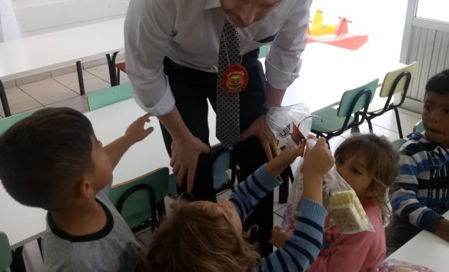 Policial civil entregando doces para crianças na sala de aula