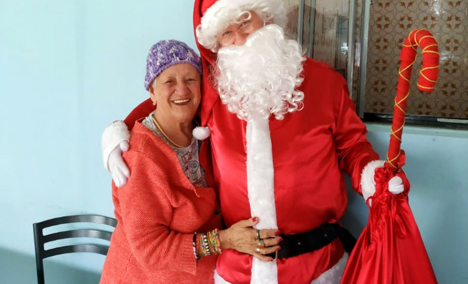 Senhora sorrindo abraçada no papai noel