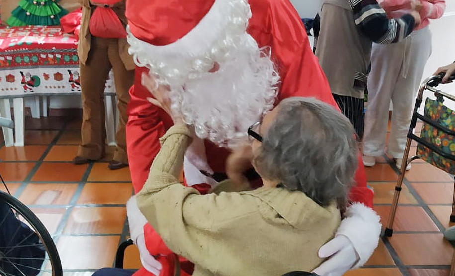 Senhora fazendo carinho em Papai Noel durante entrega de presente