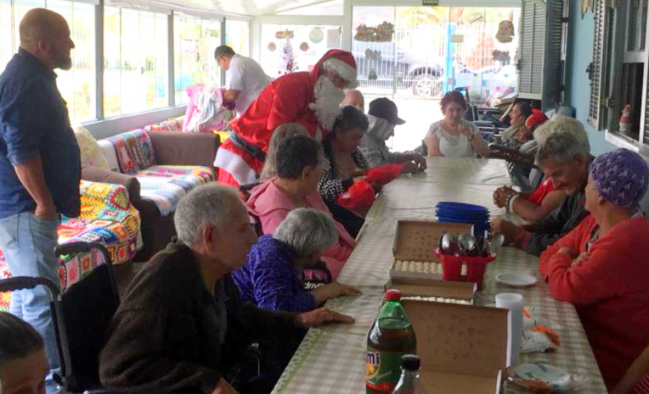 Papai Noel cumprimentando idosos do lar na mesa de refeição