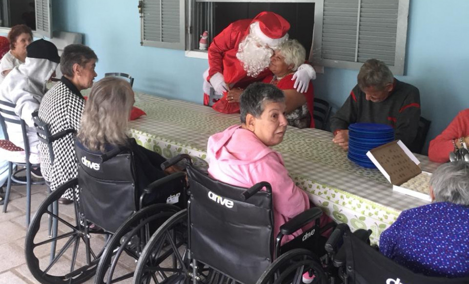 Papai Noel cumprimentando idosos do lar na mesa de refeição