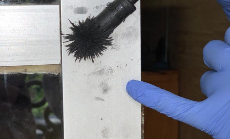 Mão de papiloscopista da PCPR manuseando equipamento para realização de perícia em local de crime