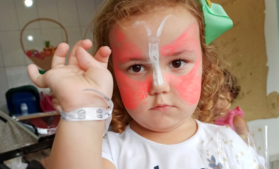 Criança exibindo uma fita enrolada no braço, com logo da polícia civil