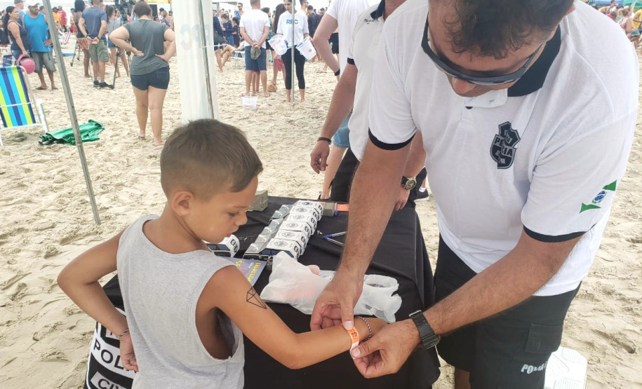 Policial civil coloca pulseirinha em braço de criança