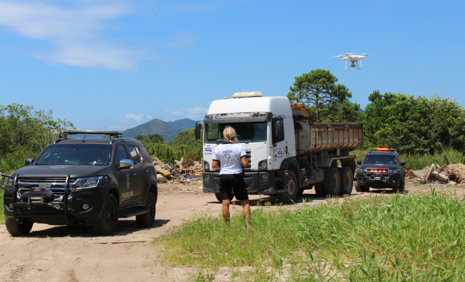 Policial civil observa caminhão entre duas viaturas