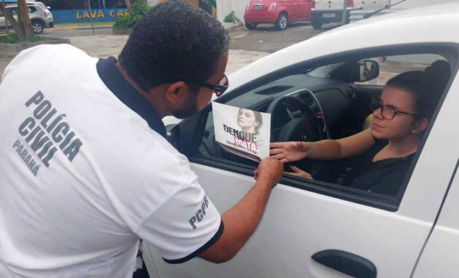 Policial civil entregando panfleto sobre dengue para motorista