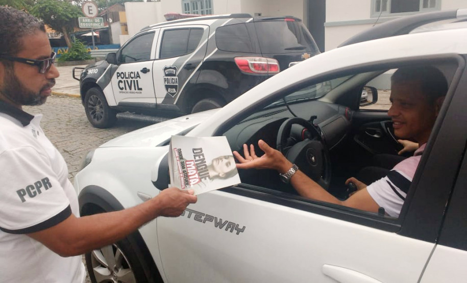 Policial civil entregando panfleto sobre dengue para motorista