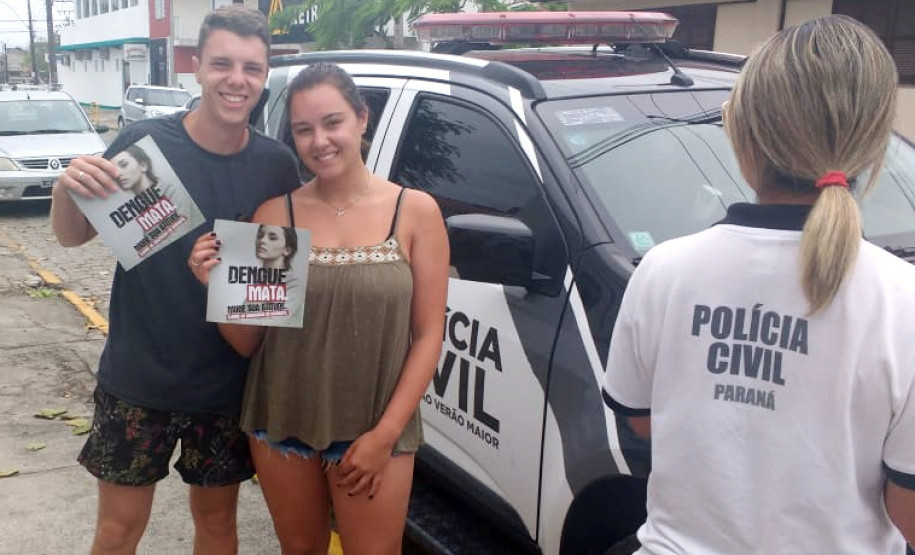 Dois veranistas exibindo panfletos sobre dengue, entregues pela polícia civil