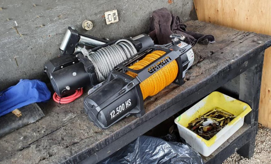 Dois guinchos de cabo de aço sobre uma bancada e caixa com ferramentas