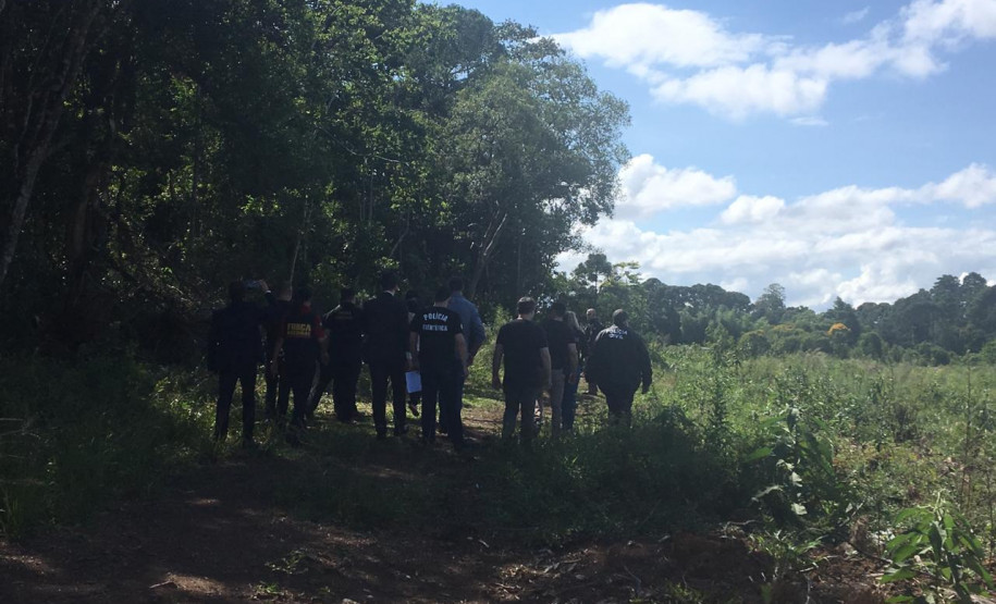Agentes da segurança caminhando em local da reconstituição do crime
