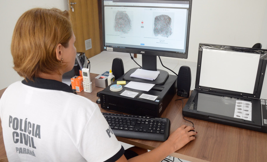 Policial civil ao computador, trabalhando no sistema de identificação