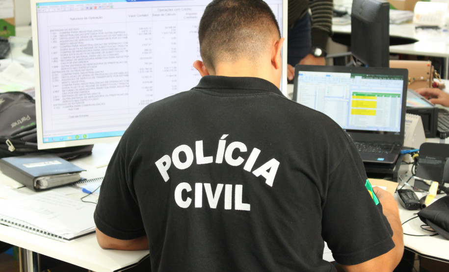 Policial civil sentado, em frente à computadores