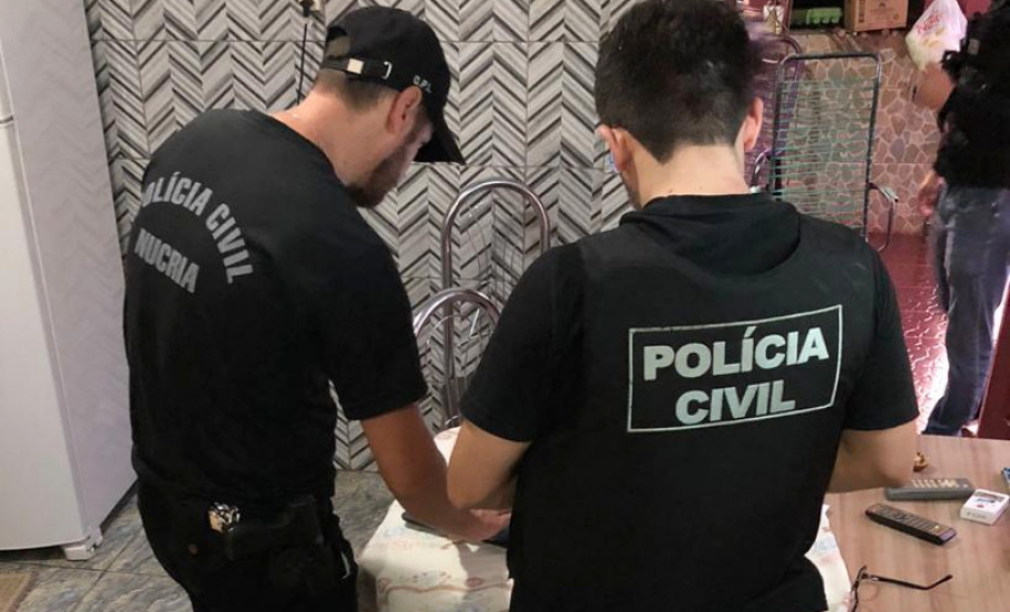 Policiais civis recolhendo notebook em residência