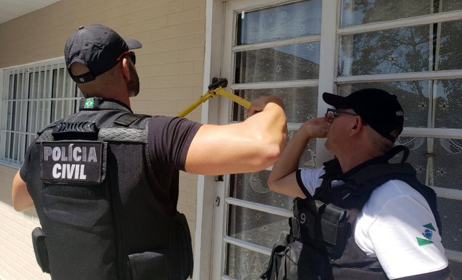 Policiais civis arrombando porta para investigação do local