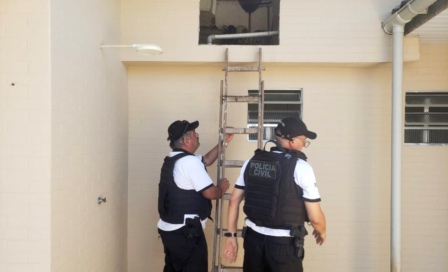 Policiais civis posiciando escada para averiguação de local alto.