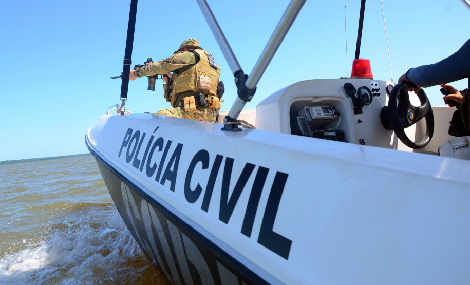 Policial civil empunhando fuzis em barco da corporação