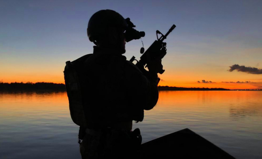 Contraluz de policial civil empunhando fuzil em barco da corporação