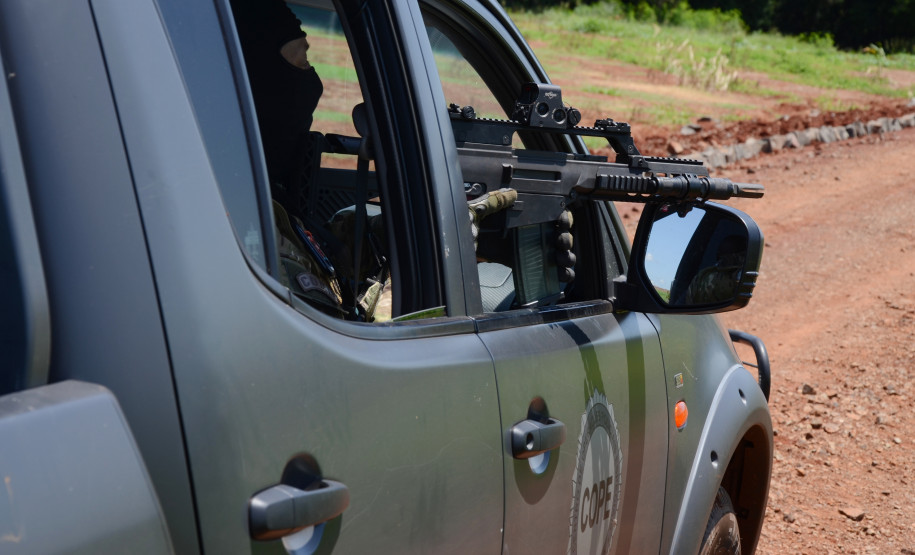 Policial civil em viatura, apontando fuzil