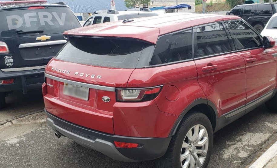 Veículo Range Rover estacionado ao lado de viatura da polícia civil