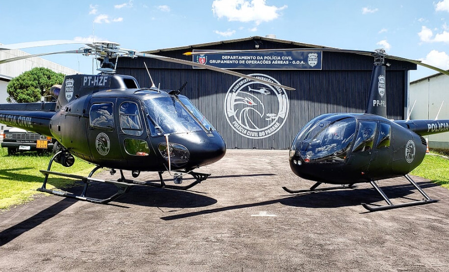 Dois helicópteros da polícia civil em frente ao hangar