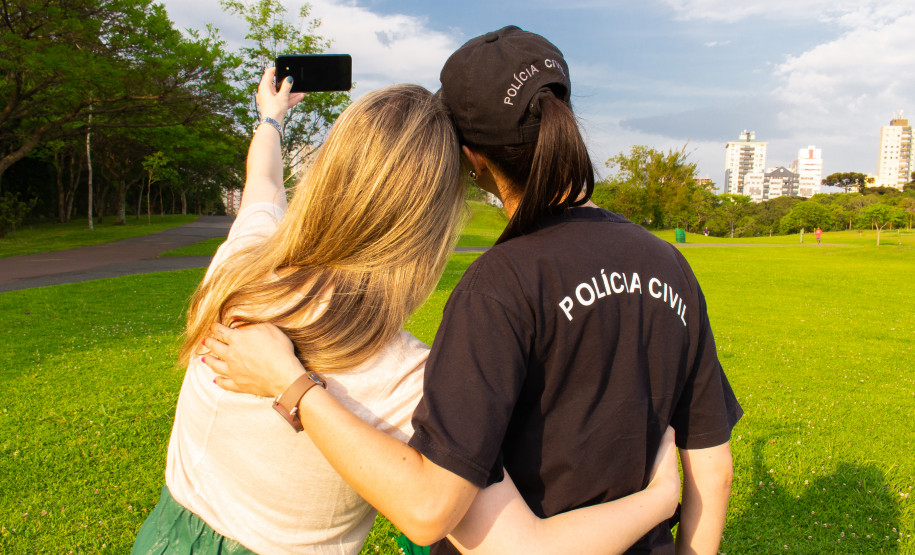 Uma mulher fazendo um selfie junto a uma policial civil
