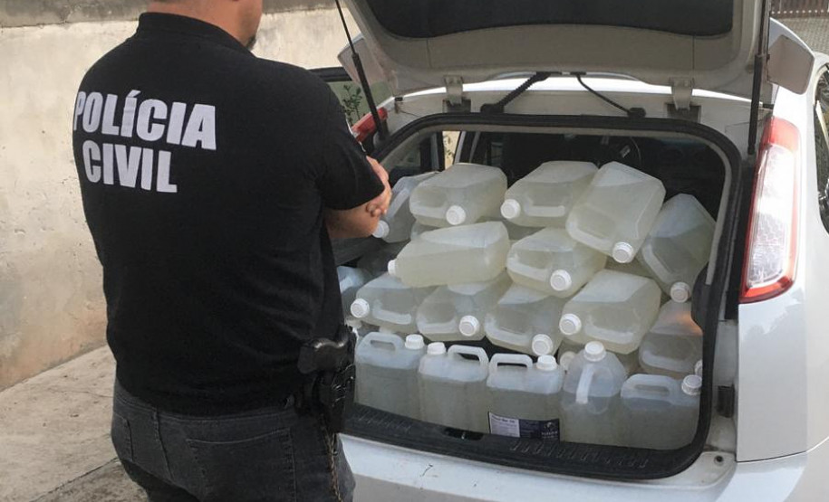 Policial observa garrafas com produto adulterado