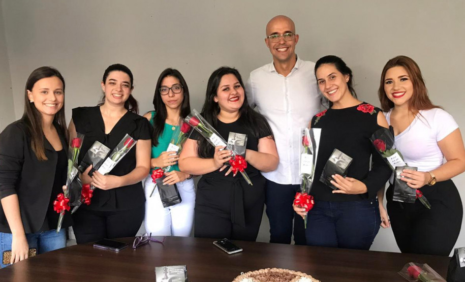 Seis mulheres segurando rosas vermelhas posando para foto junto ao delegado