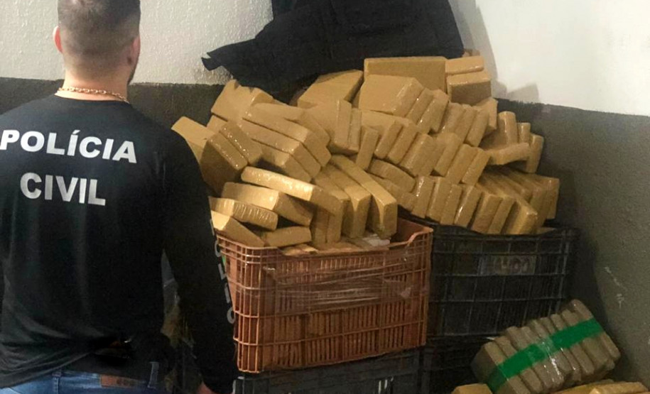 Policial civil em frente à dezenas de tabletes de drogas