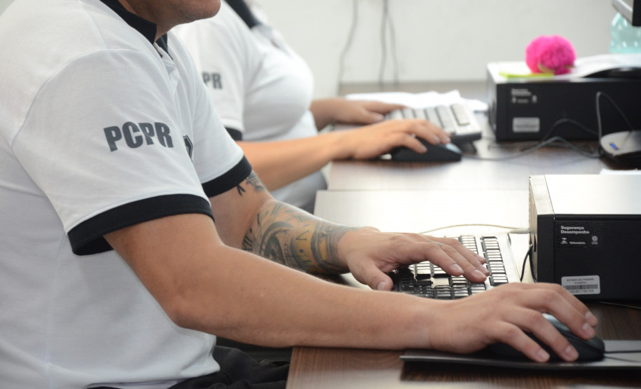 Dois policiais civis sentados, ao computador