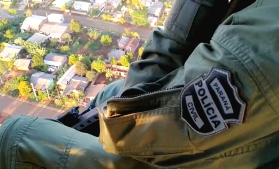 Policial civil do Grupo de Operações Aéreas em voo de helicoptero observando a região