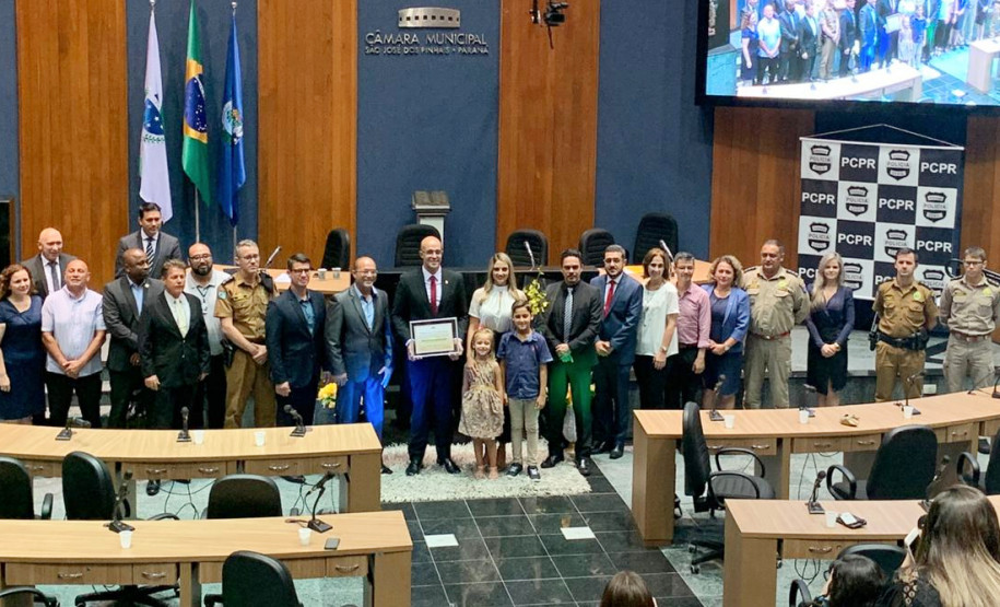 Delegado segurando o diploma junto aos participantes, posando para foto