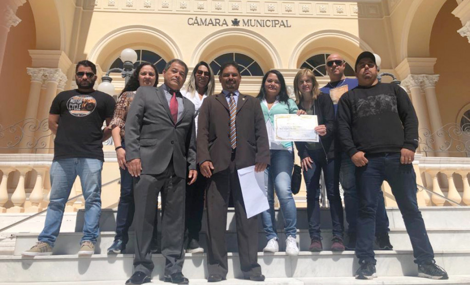 Homenageado e demais participantes posando para foto em frente à Câmara