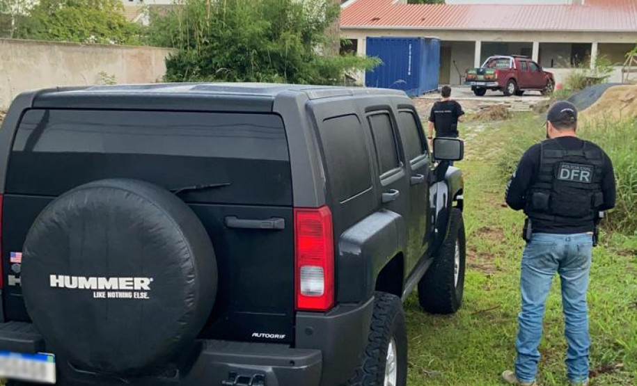 Policiais civis ao lado de veículo apreendido