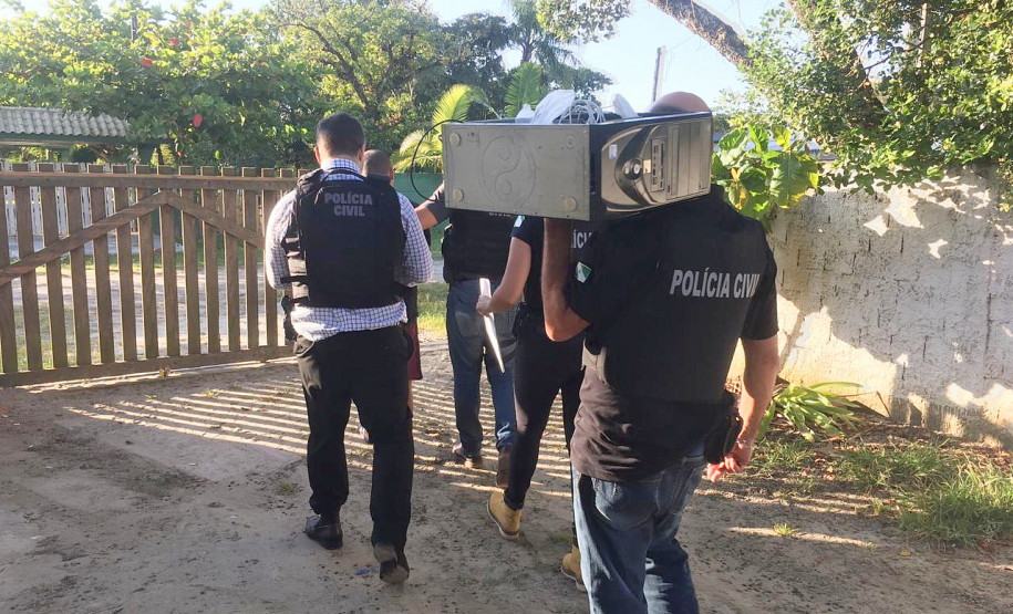 Policiais civis levando computador apreendido