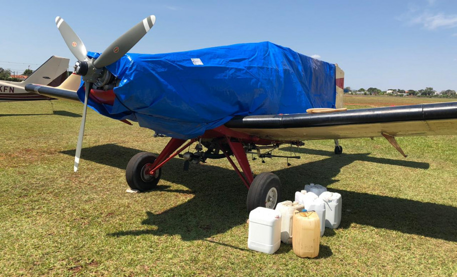 Avião apreendido, coberto com capa e alguns galões ao lado