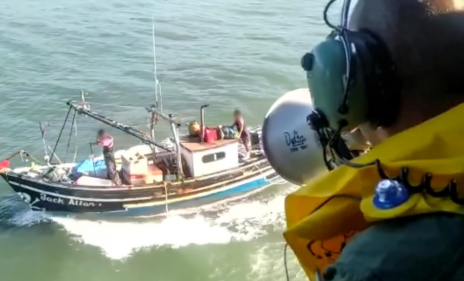 Policial civil em helicóptero alertando pescadores com megafone